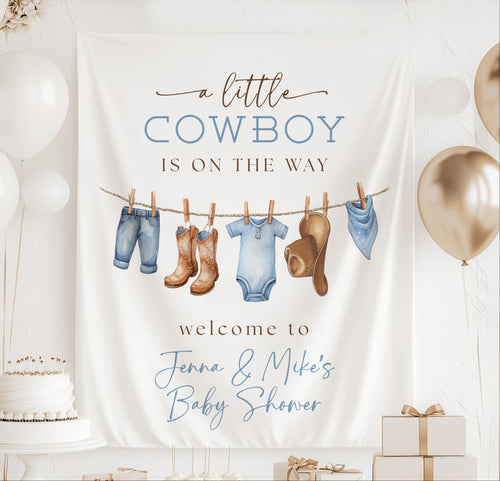Personalized A Little Cowboy Is on the Way baby shower banner with western baby clothes and cowboy accessories
