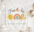 Personalized Fun to Be One first birthday banner featuring a colorful rainbow, sunshine and custom birthday details.