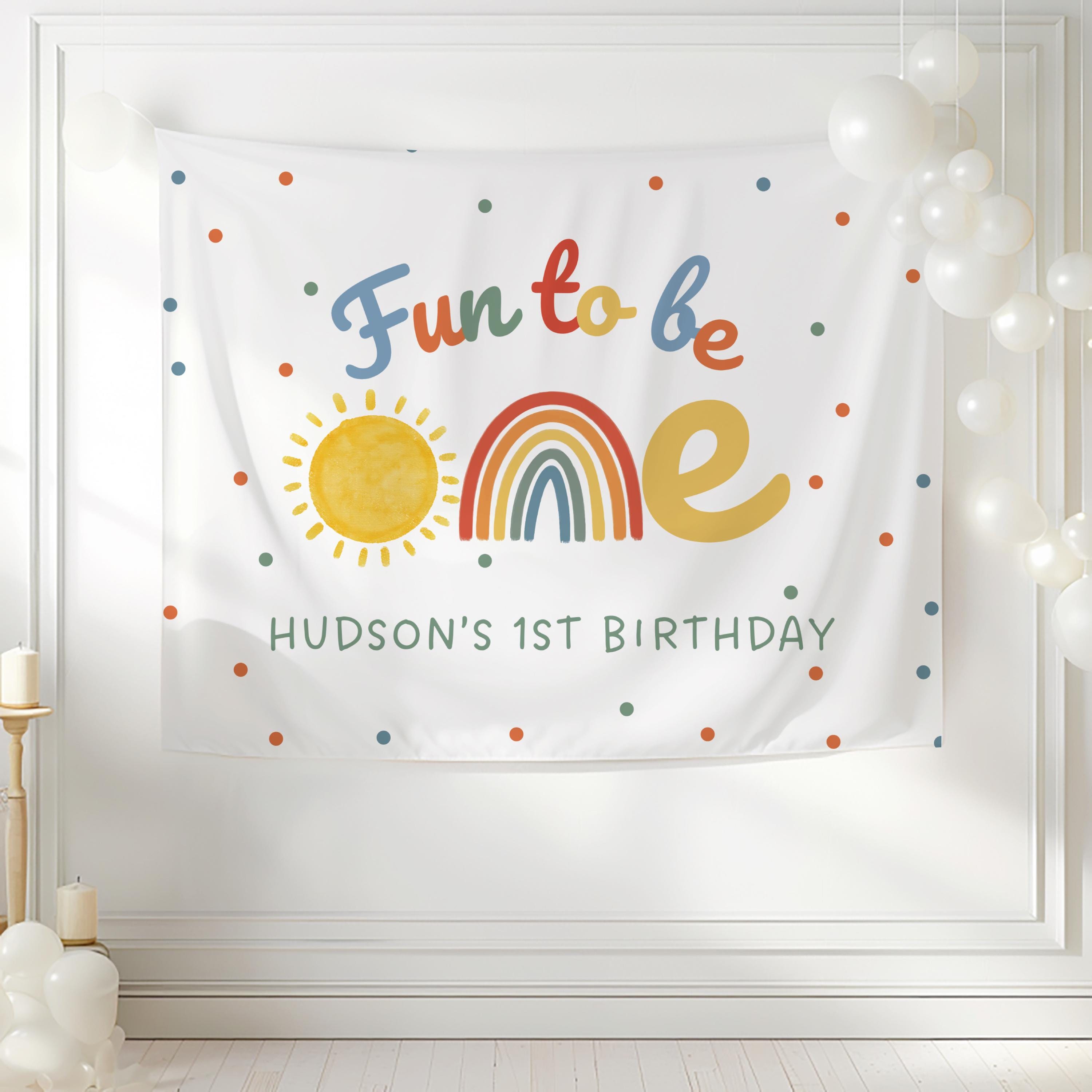 Personalized Fun to Be One birthday backdrop with rainbow, sunshine and colorful confetti for a first birthday celebration.