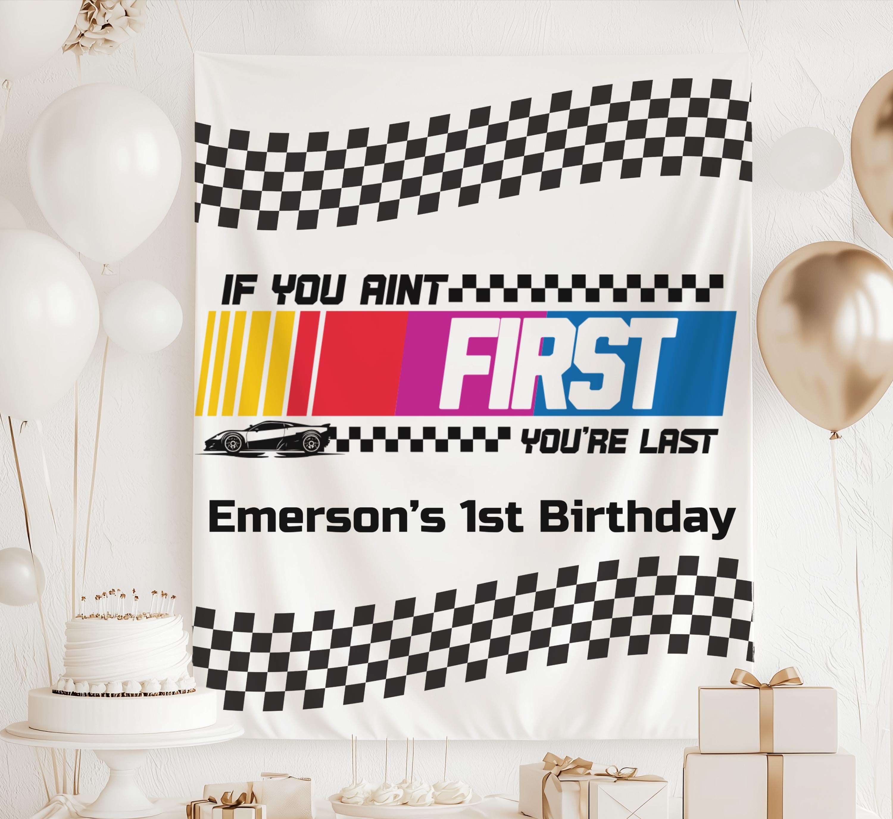 Race car themed first birthday backdrop with checkered flag design, race car illustration and personalized party decorations.